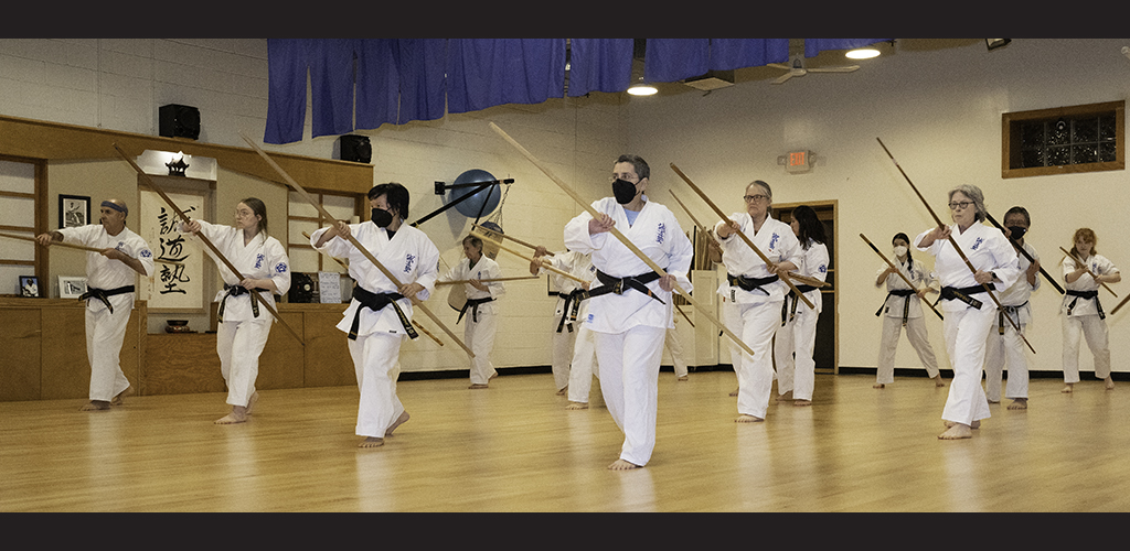 Thousand Waves' Seido Karate black belts in lines with bo (staffs) doing a rear strike or block in front of the Shinzen (spirit center of the dojo)